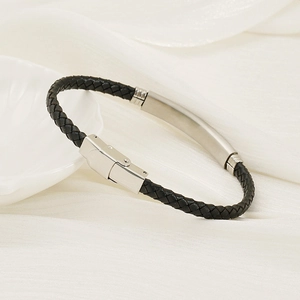 Detail eines schwarzen Lederarmbands mit poliertem Silberverschluss auf weißer Seide