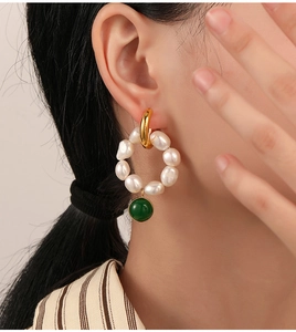Detail of vintage earrings with freshwater pearls and green beads on a female model