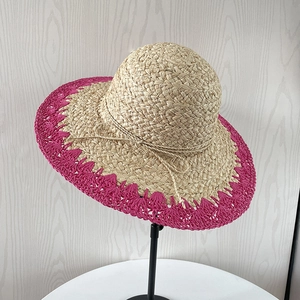 Détail d'un chapeau de soleil en raphia fait main avec bords roses festonnés et petit nœud