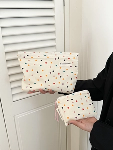 Detailed view of beige canvas cosmetic bags with colorful polka dots in two sizes