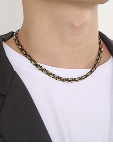 Close-up of a 5mm black and gold stainless steel Byzantine chain on a male model