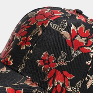 Macro shot of gold and red floral embroidery details on a black baseball cap surface