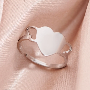 Polished silver heart ring with open adjustable band on elegant pink silk background