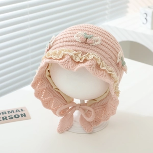 Detail of baby knit hat with delicate lace trim and crochet cherry accents in soft pink