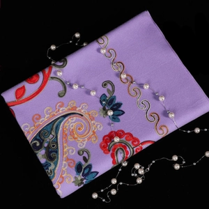 Detail of purple pashmina scarf with colorful floral paisley embroidery and pearl necklace