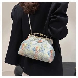 Detail of embroidered brocade bag with pearl handle worn by a model in back side view