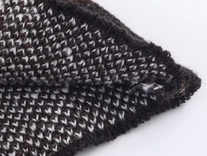 Detailed close-up of mixed brown and white yarn knitted fabric showing textured weave patterns