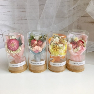 Close-up of four assorted mini dried flower bouquets inside glass jars with cork bases