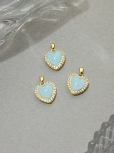 Close-up of light blue resin heart pendant with gold plating and white zircon border