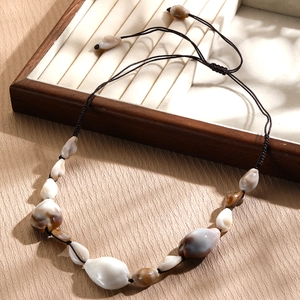Detail of bohemian seashell necklace with natural conch shells and brown woven cord