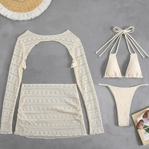 Flat lay of off-white lace bikini 4-piece set with long sleeve cover-up and beach skirt