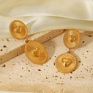 Detailed view of gold 18K plated heart earrings with radiant texture on stone surface