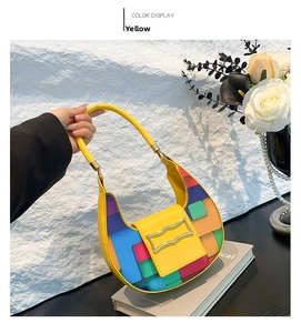 Detail of yellow crescent bag with mosaic geometric patterns and silver wavy buckle