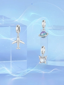 Detailed view of silver airplane, starry planet, and lavender butterfly charms for jewelry