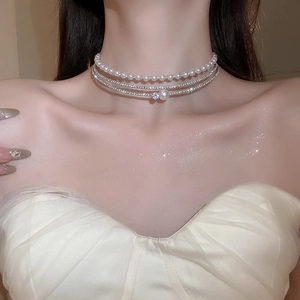 Detail of layered pearl choker with silver diamond chains and flower pendant on model