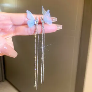 Detailed close-up of light blue butterfly wings and sparkling tassel rhinestone earrings