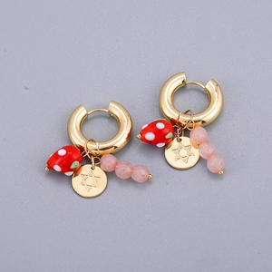 Detail view of gold hoop earrings with strawberry charm, star disc and pink beads