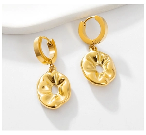 Detailed macro view of gold-plated irregular textured earrings on a marble surface