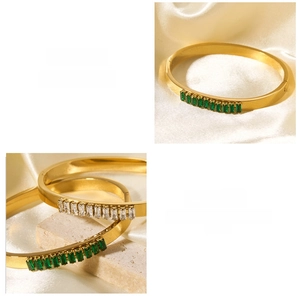 Detail view of gold-plated stainless steel bracelets with green and white cubic zirconia