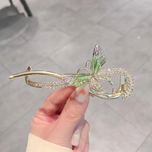 Detailed macro shot of a gold butterfly hair clip with green wings and shiny rhinestones