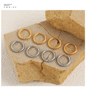 Detailed close-up of twisted spiral hoop earrings in gold and silver on a stone base