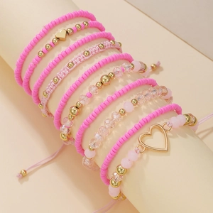 Pink bohemian beaded bracelet set with heart charms and gold accents on display