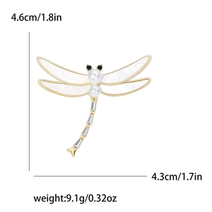 Elegant gold dragonfly brooch with white shell wings, pearls, and crystals on white background