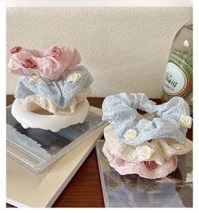 Detailed view of floral scrunchies in pink, blue, and cream with rose accents
