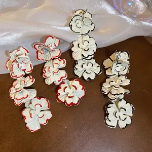 Floral tassel drop earrings with tiered lacquer petals and red or black trim on silk