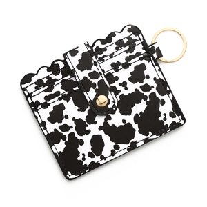 Detail of cow print leather card holder with gold snap button and metal keychain