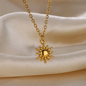 Macro shot of gold sun pendant necklace on elegant cream-colored satin fabric background