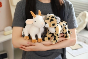 Close-up of plush white goat and spotted leopard stuffed animals held by a person