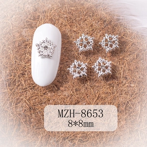 Detailed macro view of 8x8mm silver snowflake nail charm with center rhinestone on white nail