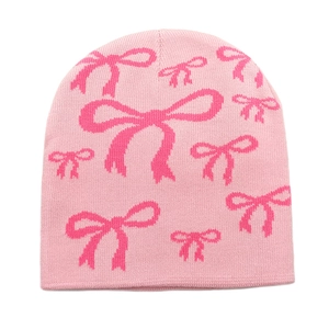 Close-up of pink knitted beanie with jacquard bow patterns and soft wool texture