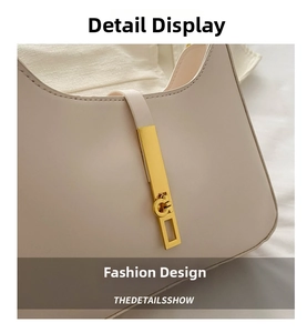 Detail of cream white leather underarm bag featuring a long golden metallic buckle