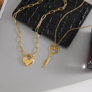 Détail de colliers avec pendentifs cœur serrure et clé dorés et perles sur cuir noir