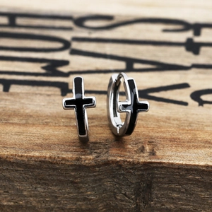Macro shot of silver and black cross-shaped stainless steel hoop earrings on wood