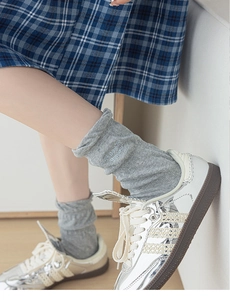 Close-up of grey ribbed mid-calf socks with Bonjour embroidery and silver metallic sneakers