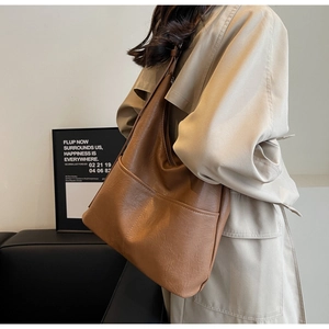 Detail of tan bucket bag showing fine faux leather texture and front double pockets