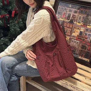 Detail of red checkered canvas tote bag with button pocket and thick fabric texture