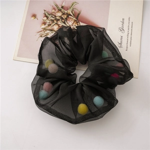Black mesh scrunchie with colorful plush balls on a clean minimalist white background