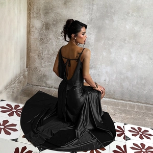 Detail of elegant black satin backless evening gown with a high slit and glossy finish