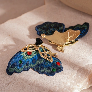 Détail de boucles d'oreilles papillon rétro avec broderie colorée et strass brillants