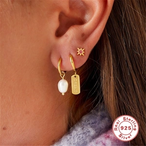 Three-piece gold 925 sterling silver earring set with pearls and star studs on ear