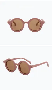Dettaglio della montura rosa opaco e lenti marroni su occhiali da sole tondi per bambini