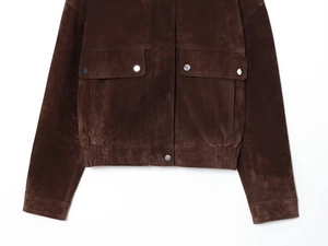 Detail of dark brown faux suede bomber jacket featuring flap pockets and metal buttons