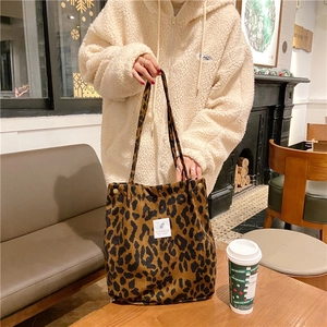 Close-up of a leopard print corduroy tote bag held by a person in a casual setting