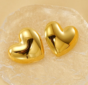 Macro shot of 3D gold heart earrings featuring a high-gloss polished mirror surface