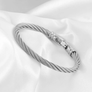 Detailed macro view of silver cable wire bracelet on elegant white satin backdrop
