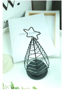 Detail of minimalist black metal LED Christmas tree with star top on a white desk